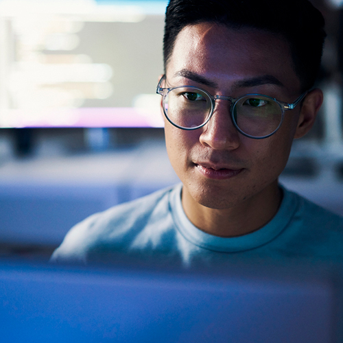 Man wearing glasses looking at laptop screen.